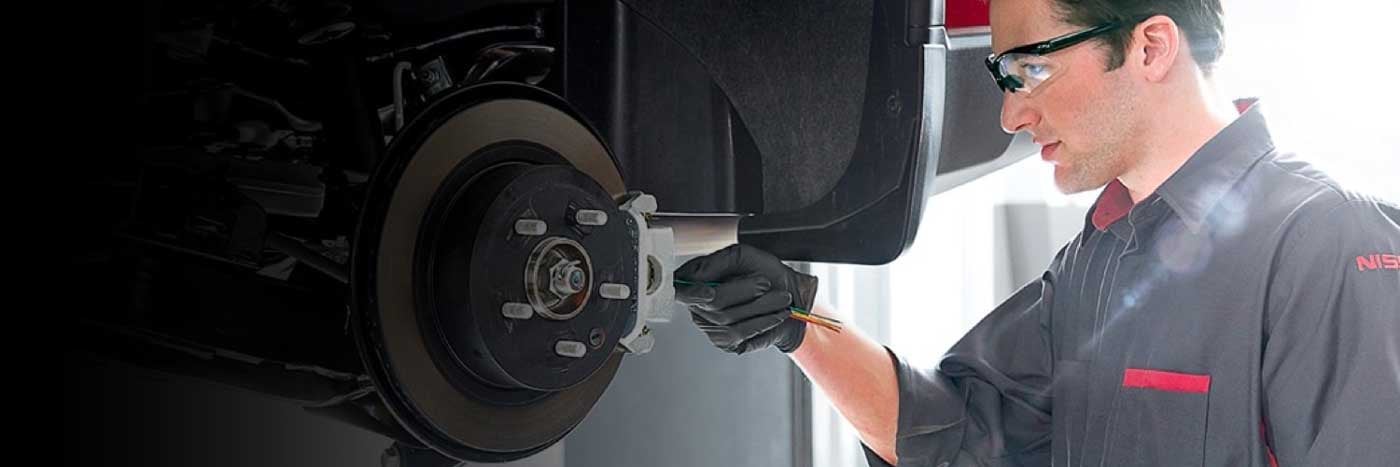 Close up view of a service tech inspecting a vehicle's brake