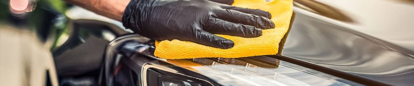 Close up view of a service tech wiping down a vehicle